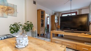 Ett modernt vardagsrum med ett TV-bord i trä, en platt-TV och en matplats med ett bord och stolar i trä.
