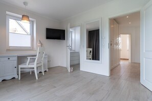 A modern room with a desk, chair, and a flat-screen TV mounted on the wall.