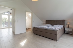 A bedroom with a bed, nightstands, and a view through an open door.