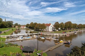 A riverside town with a lock system, a white building with a red roof, and a church spire in the background.