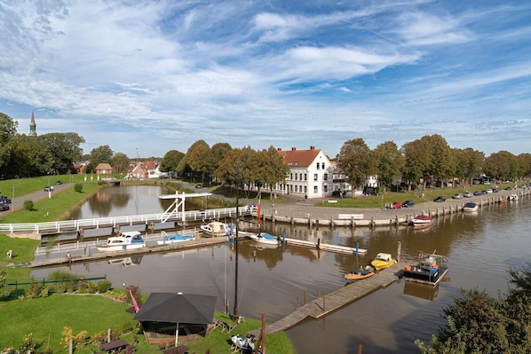 A riverside town with a lock system, a white building with a red roof, and a church spire in the background.