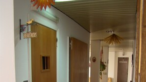 Een gang met houten deuren, een welkomstbord en een kapstok.