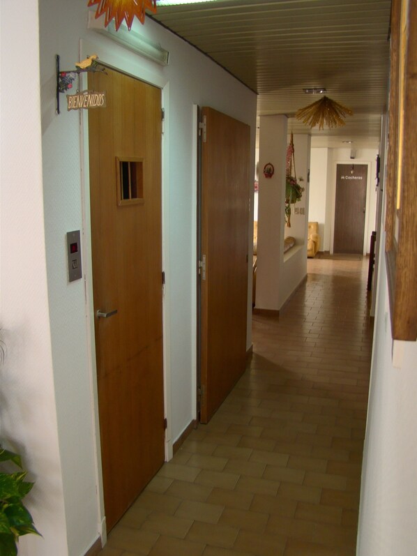 A hallway with wooden doors, a welcome sign, and a coat rack. - Hotel Internacional (Necochea)