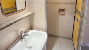 Een badkamer met een wastafel, spiegel en douchegedeelte.