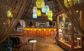 Cozy space with a high ceiling and wooden beams, featuring a bar area and comfortable seating.