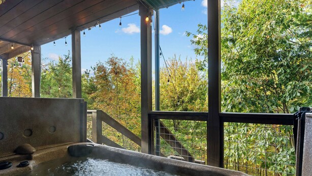 A hot tub with a wooden deck and a view of trees through a glass enclosure. - 1 Great Mountain View-3 Bed Cabin in Wears Valley (SEVIERVILLE)