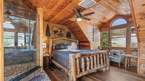 A cozy wooden cabin bedroom with a bed, a glass shower, and a view of the outside. - 1 Great Mountain View-3 Bed Cabin in Wears Valley (SEVIERVILLE)