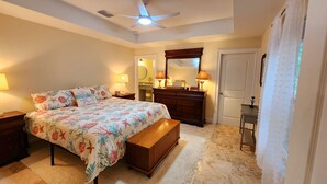 A bedroom with a bed, a nightstand, a dresser, a mirror, and a ceiling fan.
