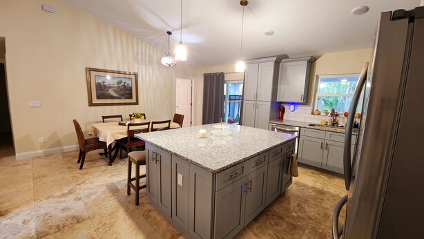 A kitchen with granite countertops, grey cabinets, and a central island.