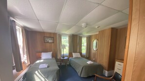 Une chambre d’hôtel avec deux lits, un bureau, une chaise et une armoire.
