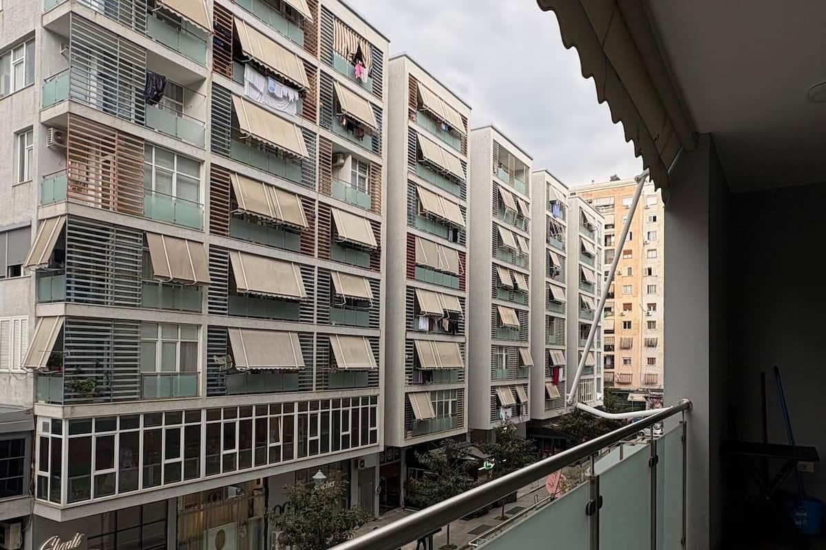 A multi-story residential building with balconies, a gated entrance, and a visible storefront.
