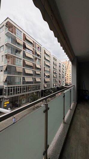 Un edificio residencial de varios pisos con balcones, entrada portón y una tienda a la vista.
