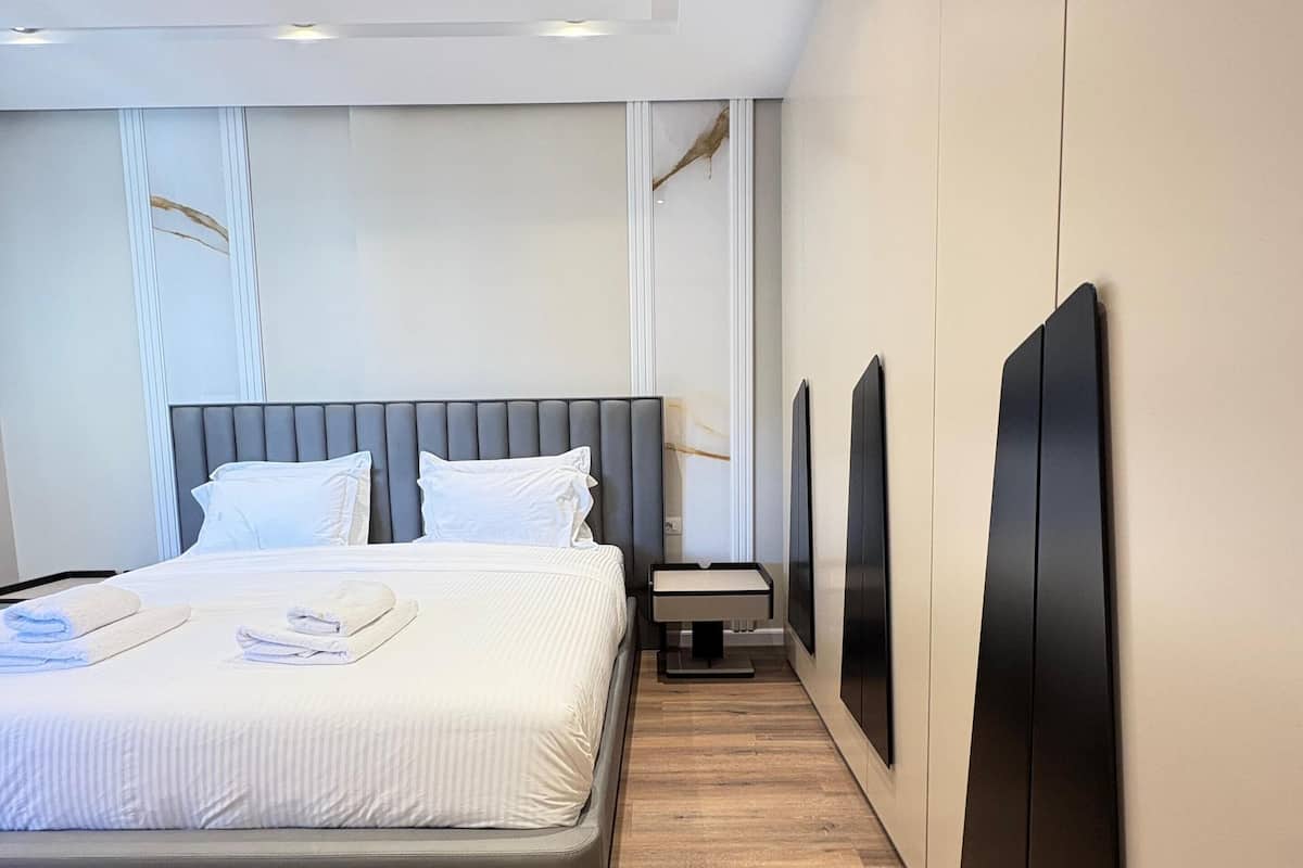 A modern hotel room with a large bed, a bedside table, and a built-in TV.