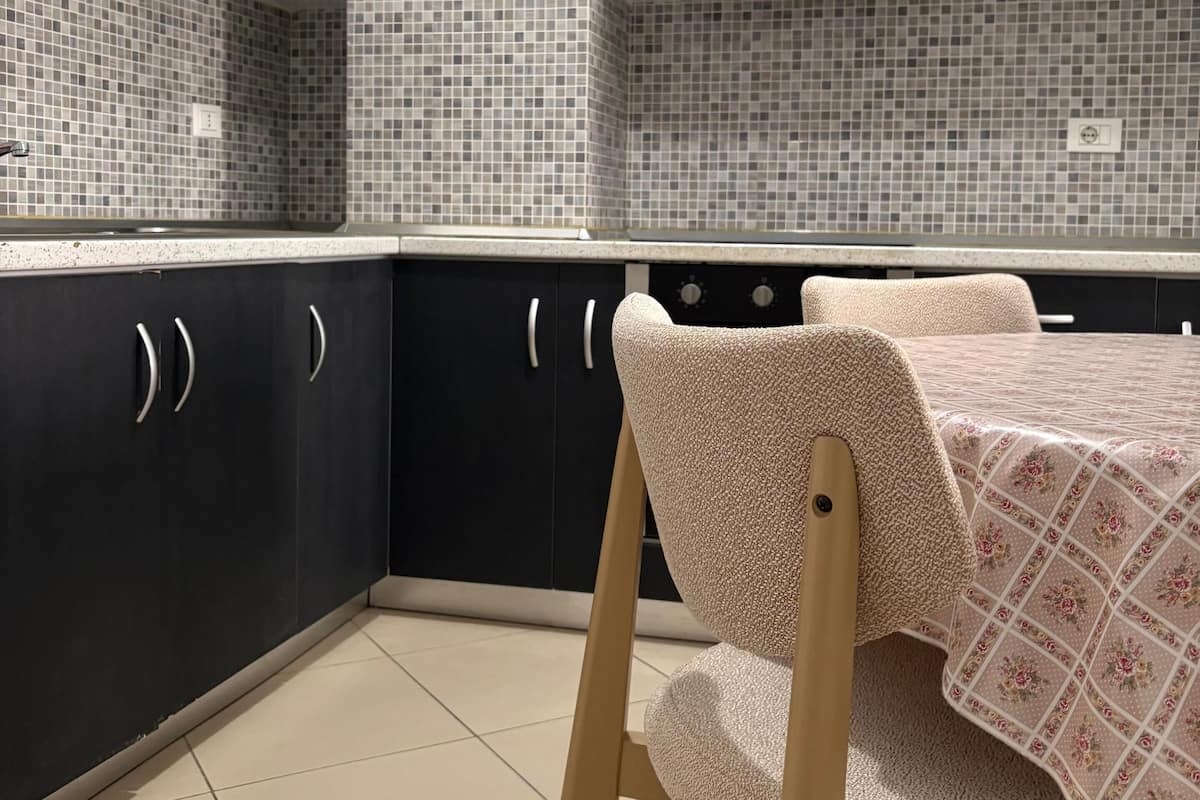 A kitchen with white and black cabinets, a tiled backsplash, and a dining area with a table and chairs.