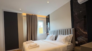 Ein modernes Hotelzimmer mit einem großen Bett, einer Sitzecke und Blick ins Freie.
