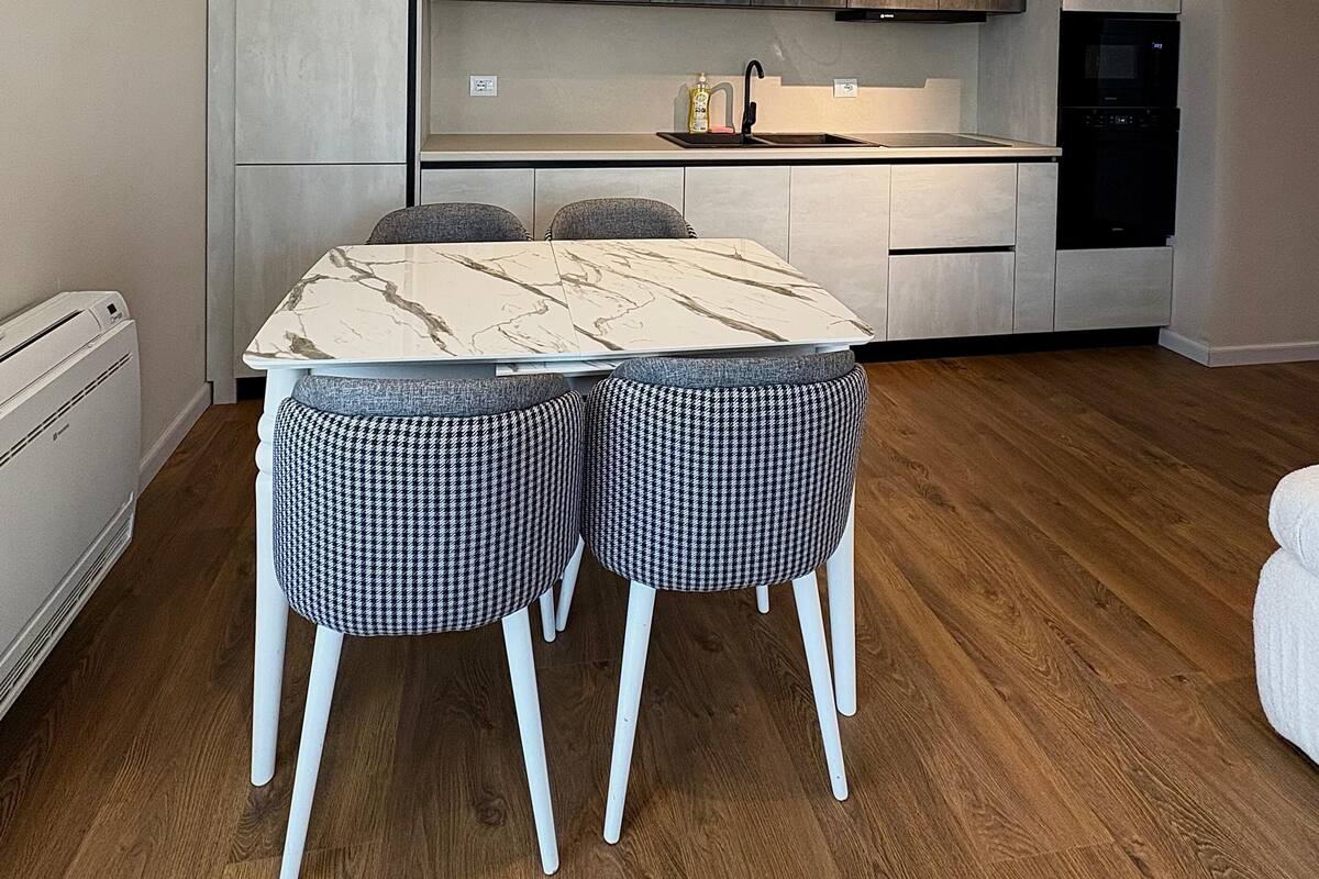 A modern kitchen with a marble-top dining table and houndstooth-patterned chairs.