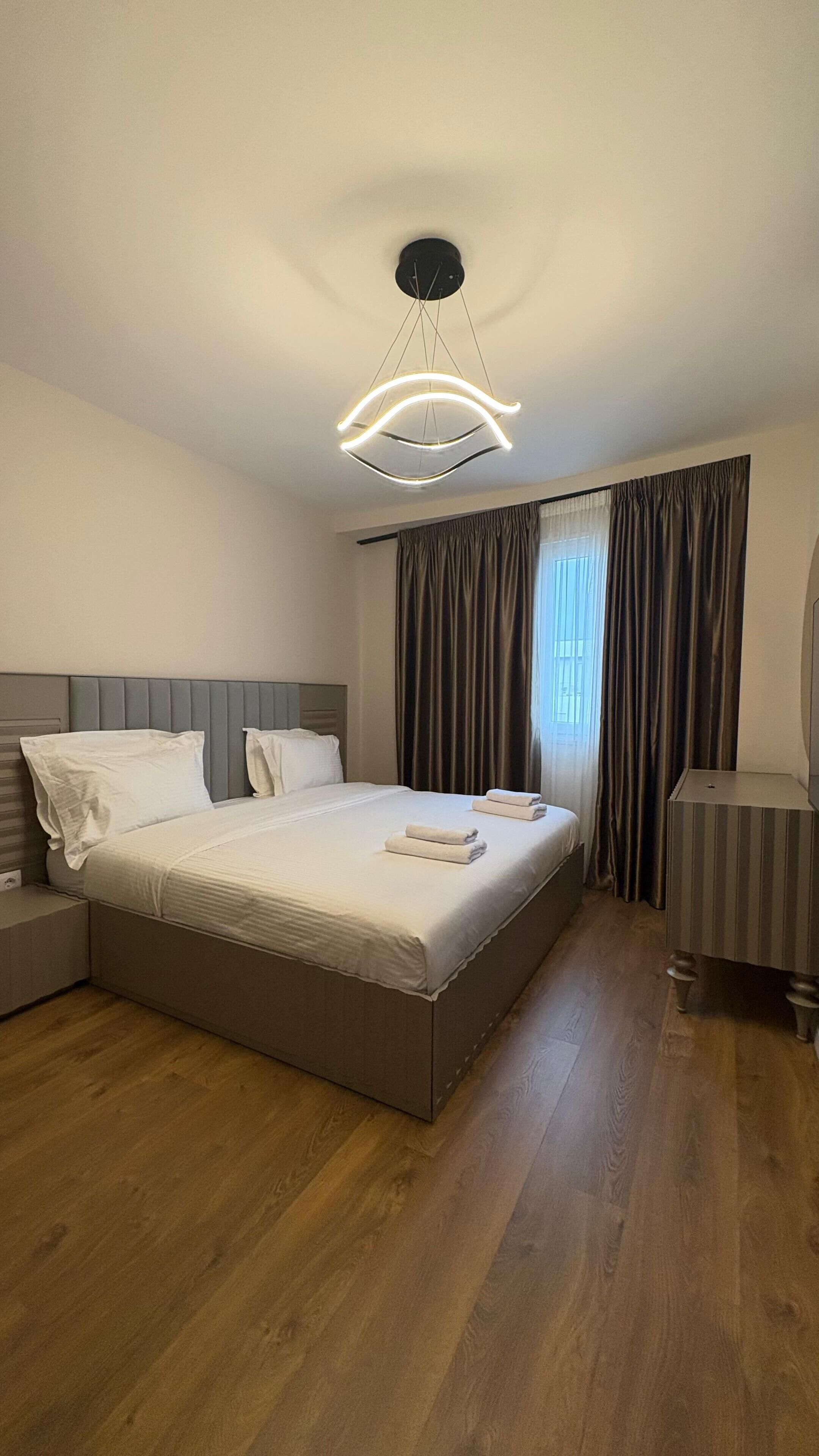 Une chambre d’hôtel moderne dotée d’un grand lit, d’une table de chevet, d’une chaise et d’un luminaire au plafond au design original.