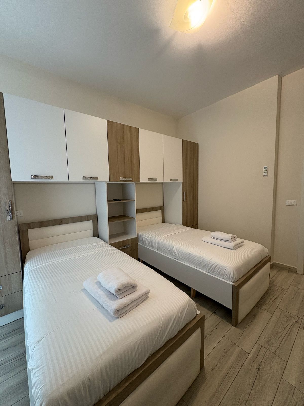 A bedroom with two beds, wooden headboards, and built-in wardrobes.