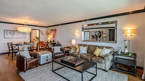 A living room with a sofa, coffee table, and a chessboard. There is a dining area with chairs and a table. - SeaCliff - Harbor View - Oceanfront Luxury in Santa Barbara (Santa Barbara)