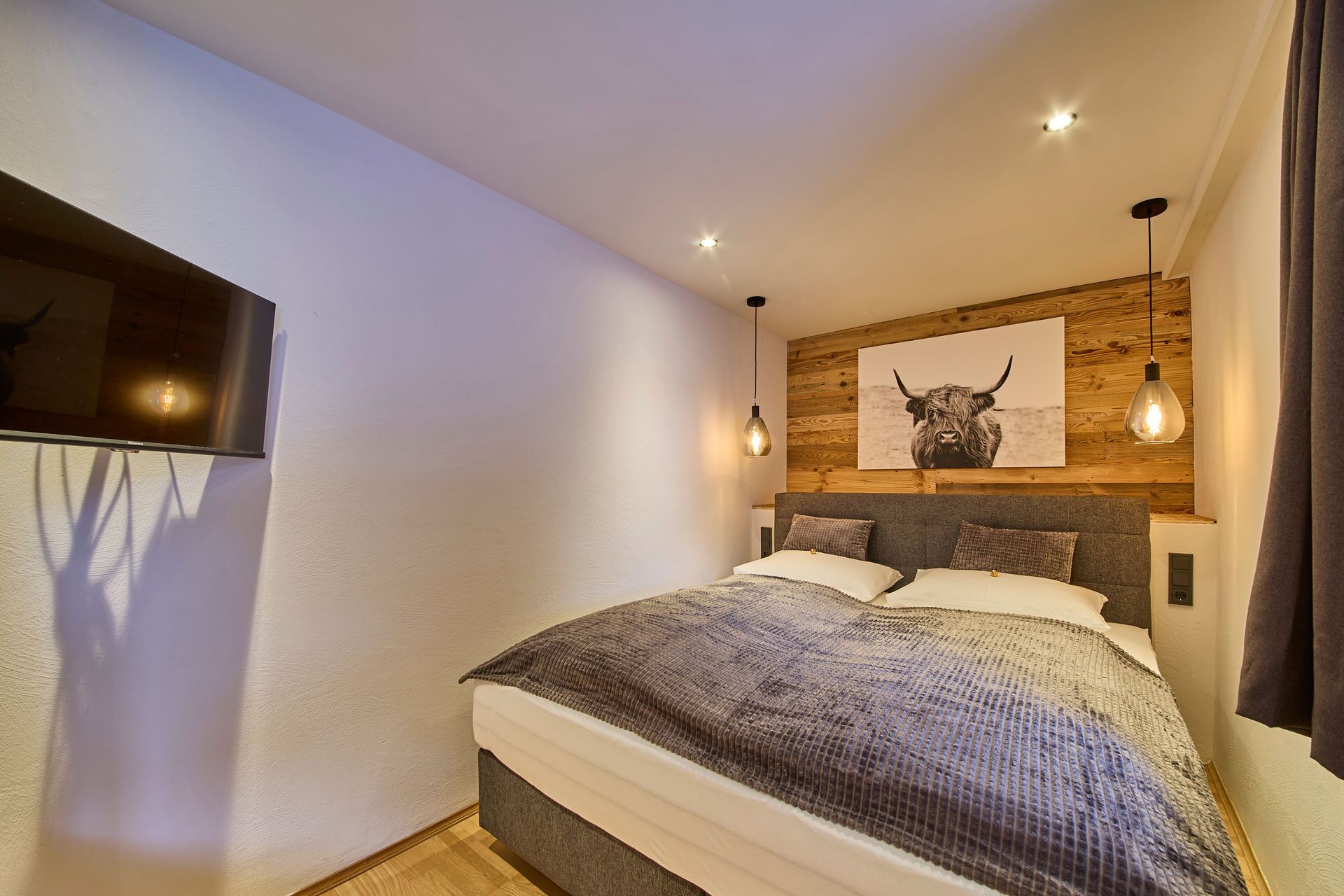 Een moderne slaapkamer met een groot bed, houten paneelwand en een stier kunstwerk.