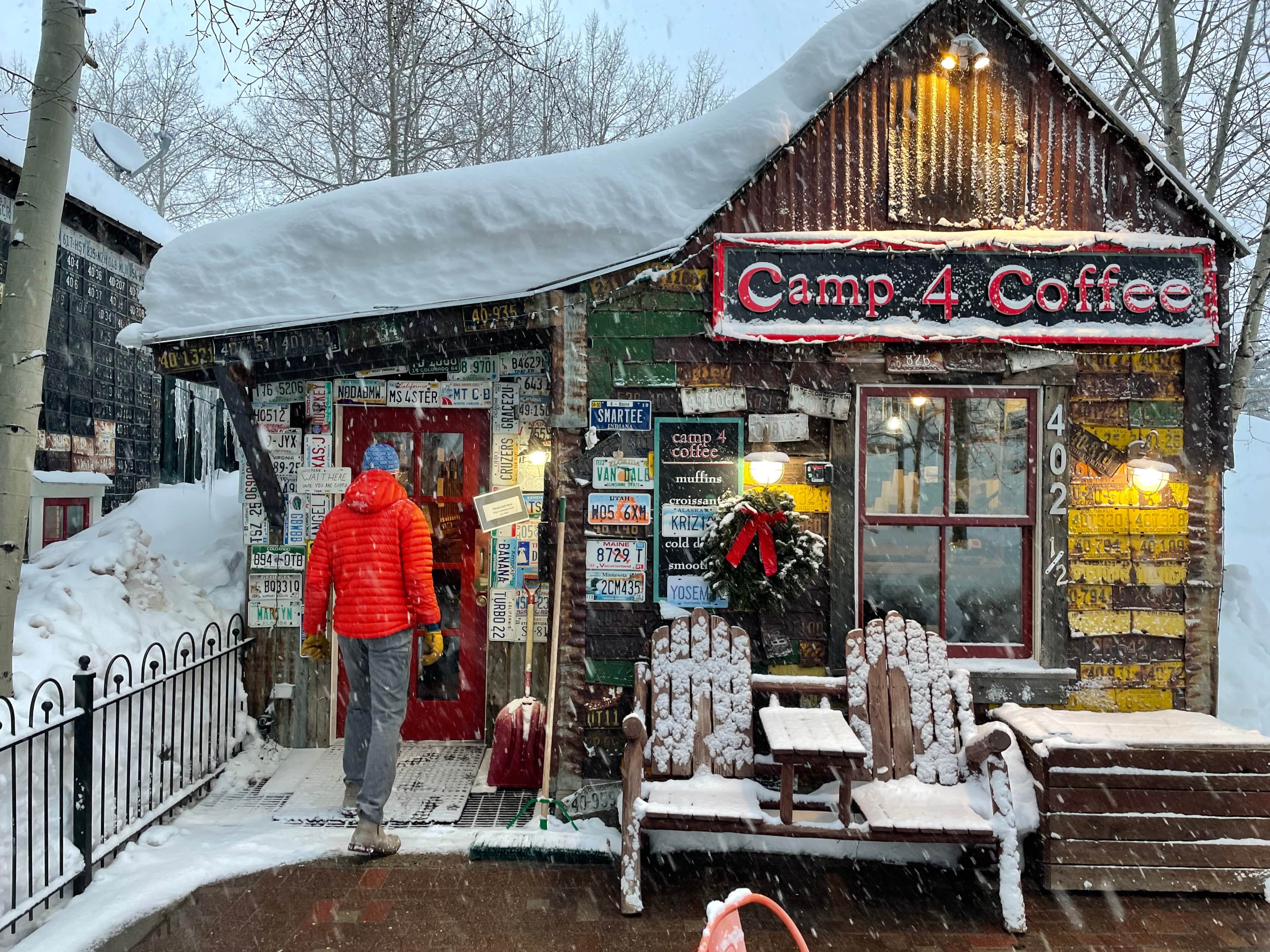 A rustic building with a sign reading 'Camp 4 Coffee' and various signs and decorations on the walls.