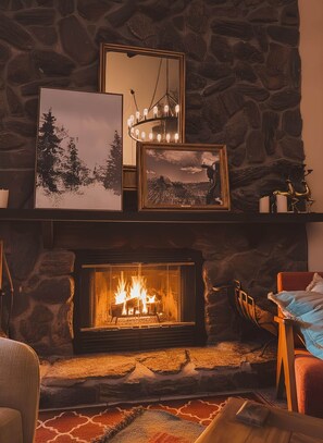 A cozy living room with a stone fireplace, framed artwork, and a chandelier. - Ski-In Ski-Out Crested Butte 3BR Condo, Pets OK (Crested Butte)