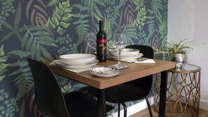 Une table à manger avec une bouteille de vin, des verres, des assiettes et une plante en pot.