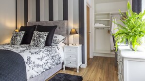 Une chambre à coucher avec un lit, des tables de chevet, une commode, un placard et une plante en pot.