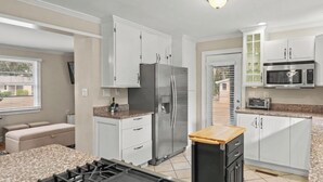 A modern kitchen with white cabinetry, a stainless steel refrigerator, a microwave, and a built-in oven. There is a small island with a wooden countertop and a sink. - Parris Island 10 min - Pet friendly Home + Yard (Beaufort)