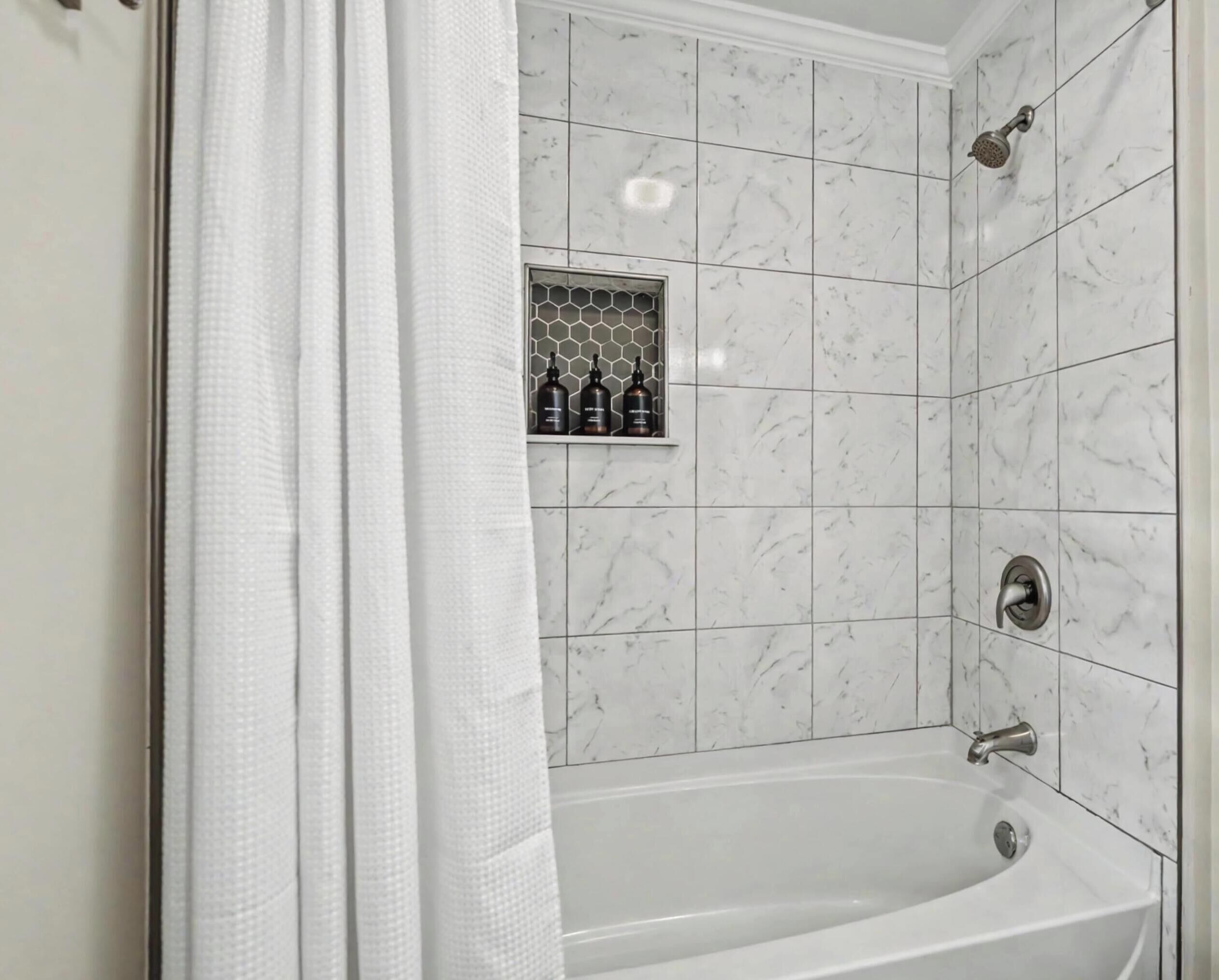 A bathroom with a white bathtub, a showerhead, and a shelf with toiletries.