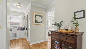 A hallway with a bench, a framed picture, a vase with a plant, and a wooden cabinet with drawers. - Parris Island 10 min - Pet friendly Home + Yard (Beaufort)