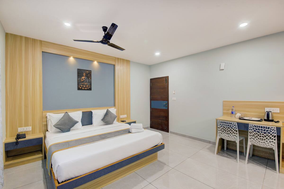 Ein modernes Hotelzimmer mit Bett, Nachttisch, Schreibtisch, Stuhl und Deckenventilator.