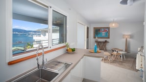A modern kitchen with a large window overlooking a marina and sea. - Horizon Bleu (Trois-Ilets)