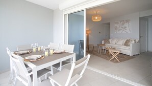 A dining area with a table set for four, a sofa, and a lamp in the background. - Horizon Bleu (Trois-Ilets)