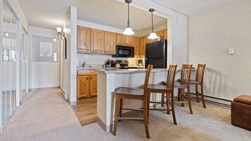 A modern kitchen with wooden cabinets, a black refrigerator, and a central island with bar stools.