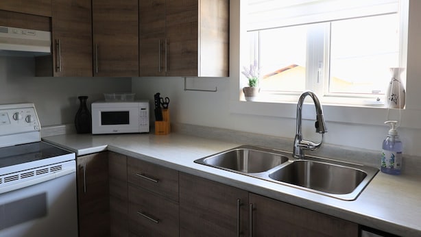 Een keuken met houten kastjes, een magnetron, een fornuis, een spoelbak en een raam met uitzicht.
