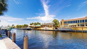 A waterfront property with a dock, boats, and a building with large windows.