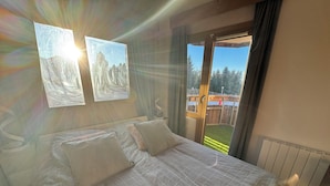 Ein Schlafzimmer mit einem großen Bett, zwei an der Wand befestigten Bildern und einer Schiebeglastür, die auf einen Balkon führt.
