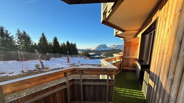 Ein hölzerner Balkon mit Blick auf schneebedeckte Berge und einen klaren Himmel.