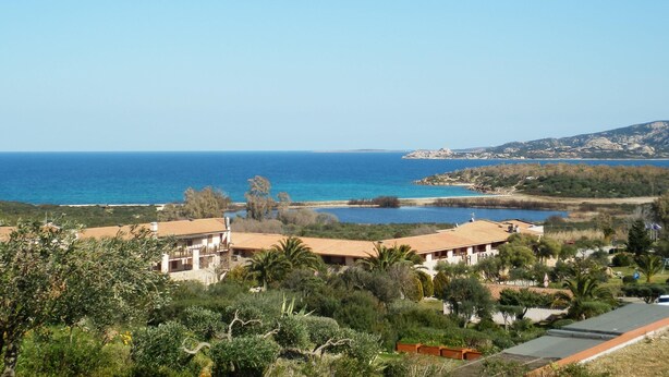 Une propriété située sur la côte, offrant une vue sur la mer, dotée d’une piscine et entourée d’un paysage vallonné.