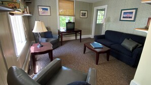 A living room with a sofa, a chair, a coffee table, a television, and a lamp.