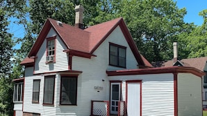 A two-story white house with a red roof and a chimney.