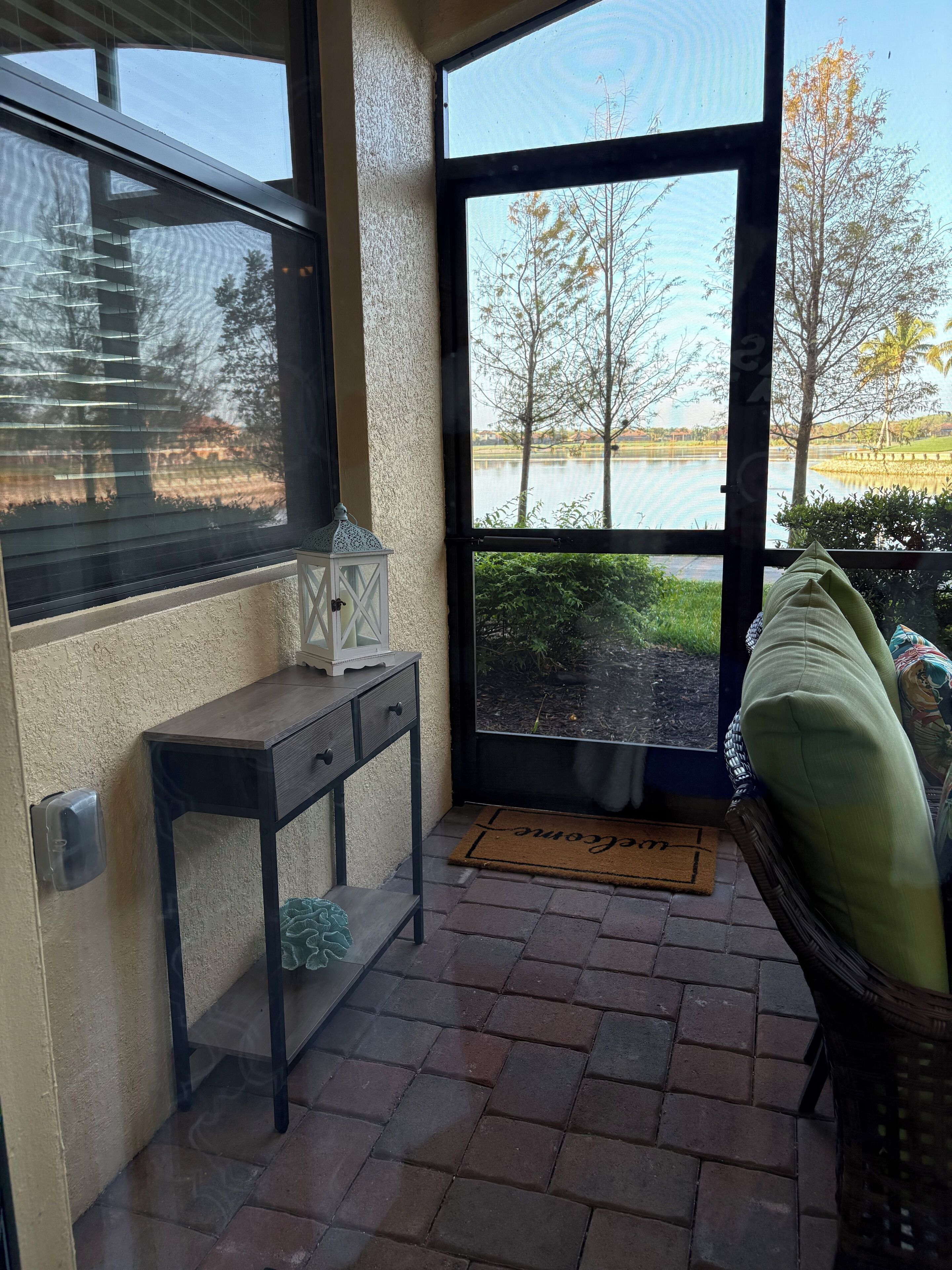 Eine überdachte Veranda mit Seeblick, ein Tisch mit einer Laterne und eine Fußmatte.