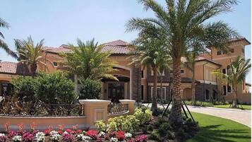 A large, multi-story building with a Mediterranean architectural style, featuring terracotta roofs and stucco walls.