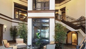 Un hall d’entrée spacieux avec une colonne centrale, un escalier et plusieurs espaces aménagés pour s’asseoir.