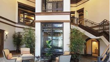 A spacious lobby with a central column, a staircase, and multiple seating areas.
