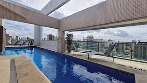 A rooftop swimming pool with a city view, lounge chairs, and a tiled deck. - Cozy 2 Bedroom Apartment. Excellent Location! (Batista Campos Belém)
