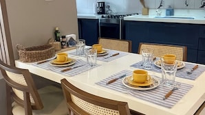 A dining area with a table set for four, equipped with chairs, plates, and cutlery. - Cozy 2 Bedroom Apartment. Excellent Location! (Batista Campos Belém)