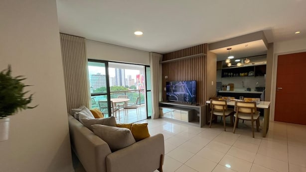 A modern living room with a sofa, a television, and a dining area with chairs and a table. - Cozy 2 Bedroom Apartment. Excellent Location! (Batista Campos Belém)