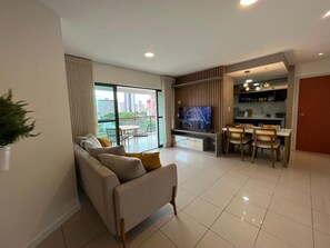 Una sala de estar moderna con un sofá, un televisor y un comedor con sillas y una mesa.